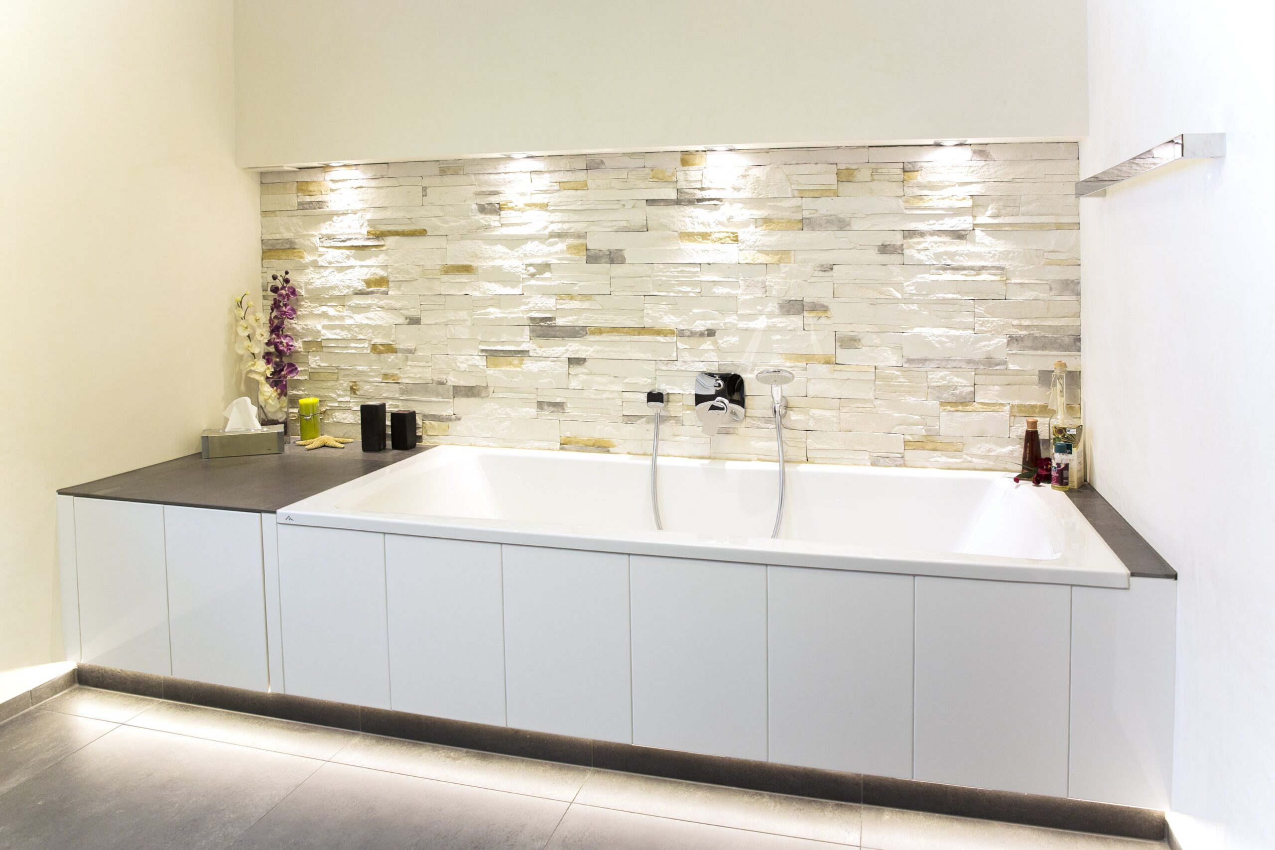 Badezimmer mit großformatigen Bodenfliesen und Natursteinwand
